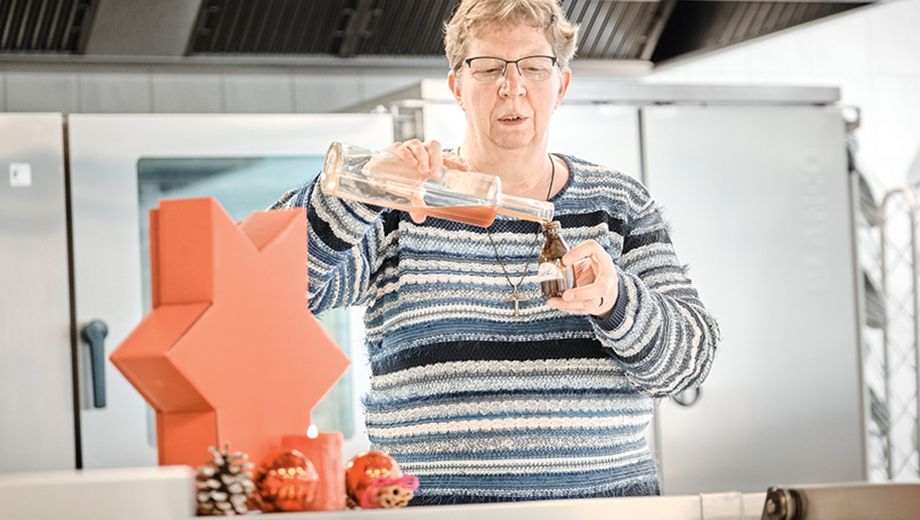 Frau schüttet Getränk in eine Flasche, weihnachtlich dekoriertes Ambiente